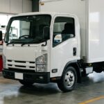 Грузовик Isuzu серии N в автосервисе с запчастями на стеллажах